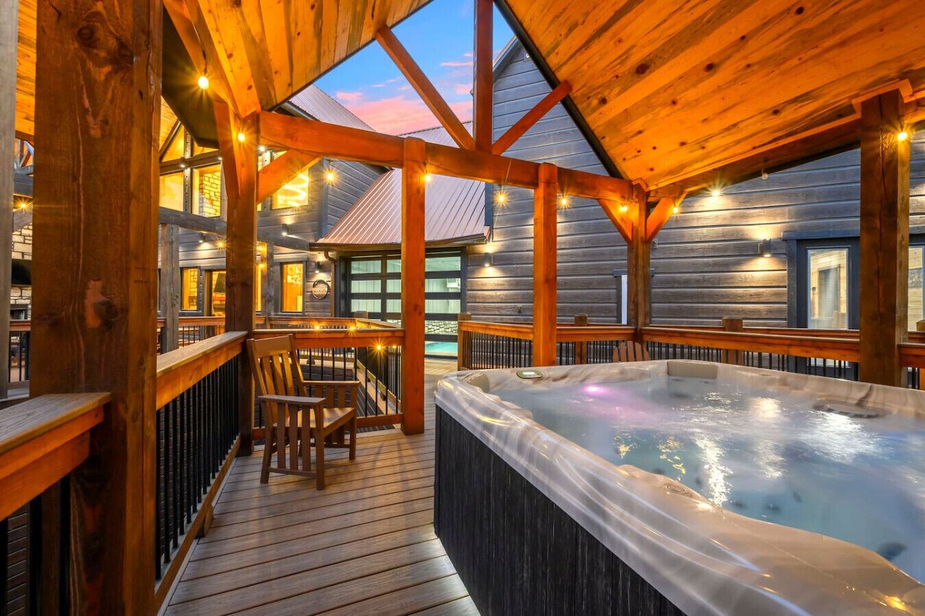 Una terraza de madera con un jacuzzi, barandas de madera y vistas al exterior.
