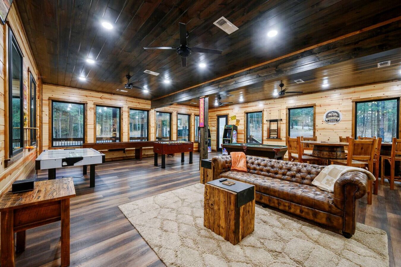 A wooden interior with a pool table, sofa, and dining area.