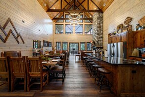 Una cocina amplia con armarios de madera, una chimenea de piedra y un comedor grande con mesas y sillas de madera.