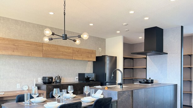 Een moderne keuken met een centraal eiland, inbouwapparatuur en een eethoek met een tafel gedekt voor vier personen.