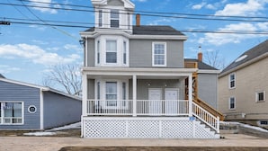 Une maison à deux étages avec un porche à l’avant, un escalier couvert et une boîte aux lettres bien visible.