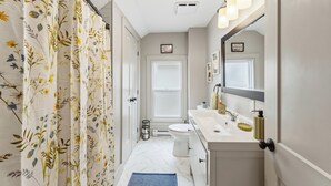Une salle de bain équipée d’un rideau de douche, de toilettes, d’un lavabo et d’un miroir.