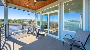 Een balkon met een plafondventilator, een stoel en een tafel met stoelen.