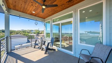 A balcony with a ceiling fan, a chair, and a table with chairs.