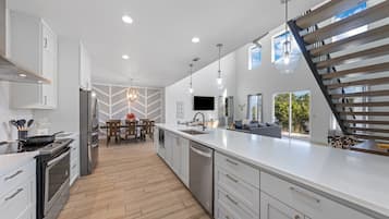 A modern kitchen with white cabinetry, stainless steel appliances, and a herringbone floor pattern.