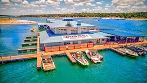 Een bootenhuis genaamd Captain Pete's met meerdere boten aanmerkt, een steiger en uitzicht op het water en de verre kustlijn.