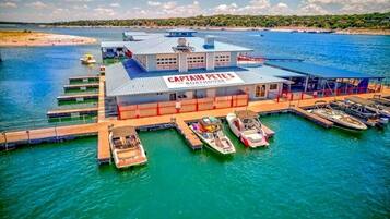 A boathouse named Captain Pete's with multiple boats docked, a pier, and a view of the water and distant shoreline.