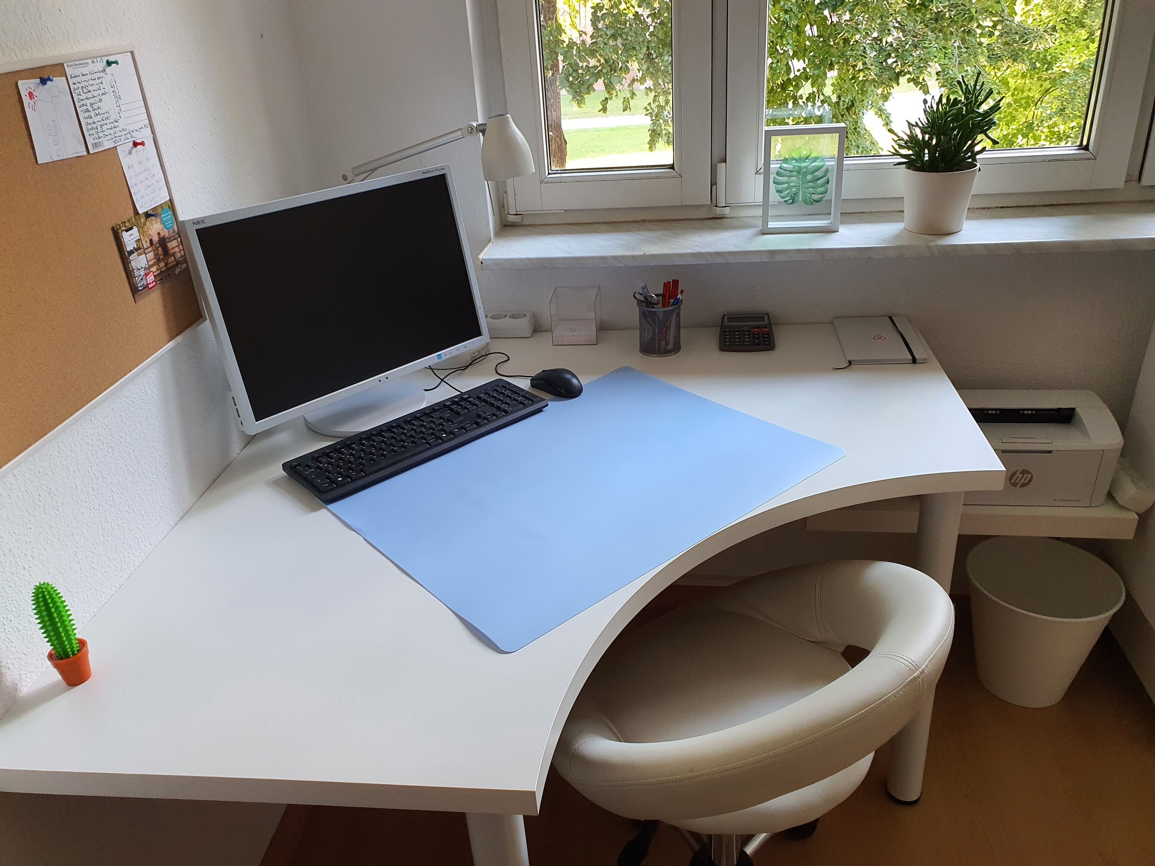 Ett skrivbord med en dator, ett tangentbord, en mus och en blå matta.