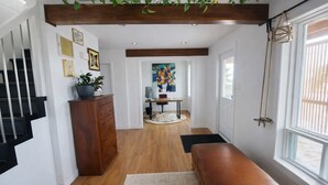 Un couloir avec un banc en bois, un bureau avec un ordinateur, une plante en pot et des œuvres d’art accrochées aux murs.
