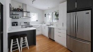 Une cuisine moderne avec des meubles blancs, des appareils en acier inoxydable et un plancher en bois.