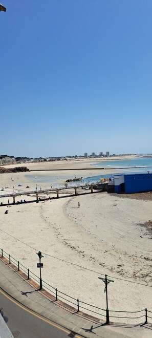 A beach with a clear sky, a sandy shore, and a blue water body.