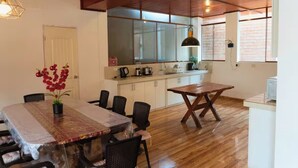 A dining area with a table and chairs, a kitchen with cabinets and appliances, and a wooden ceiling.