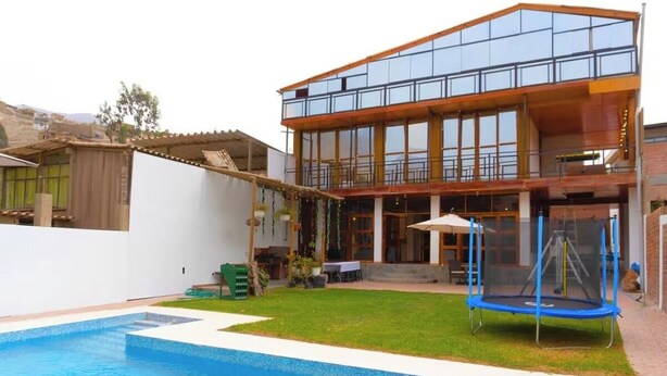 A modern house with a swimming pool, a trampoline, and a patio area.