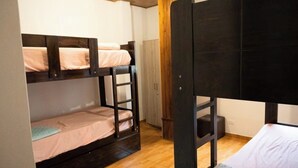A bunk bed room with a wooden floor, a wardrobe, and a door.