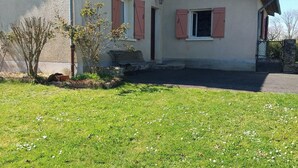 Ett envåningshus med ett sluttande tak, en liten veranda och en asfalterad uppfart.