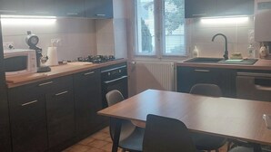 Ett modernt kök med mörka skåp, en bänkskiva i trä, en gasspis, en diskho och en matplats med stolar.