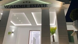 A building with a sign reading 'Vladimir Estate' and a modern architectural design with columns and recessed lighting. - Vladimir Estate (Gjirokastër)