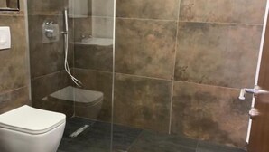 A bathroom with a glass-enclosed shower, a white toilet, and tiled flooring. - Vladimir Estate (Gjirokastër)
