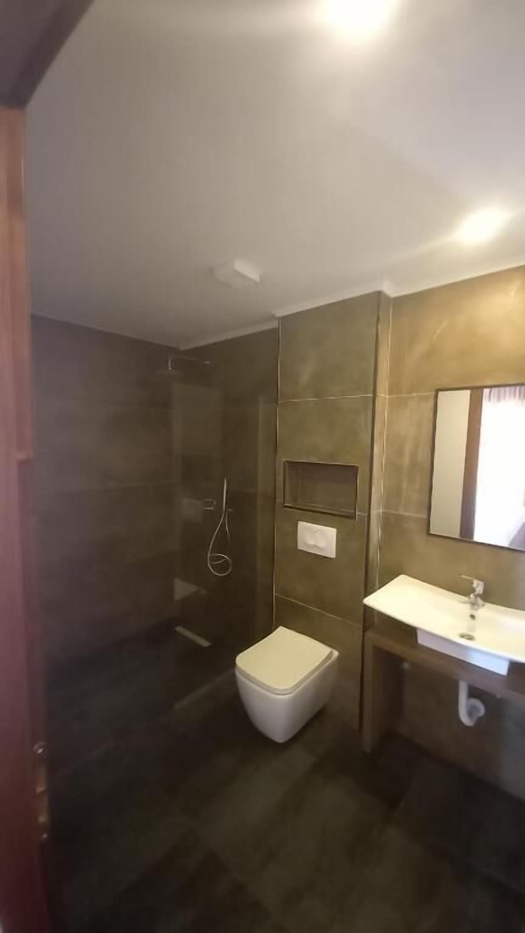 A bathroom with a shower, toilet, and sink.