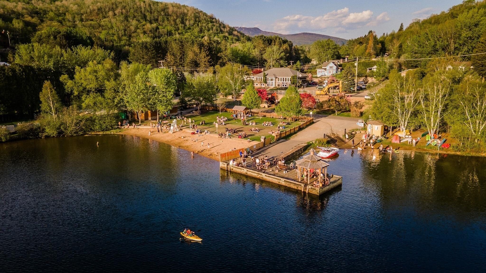 Una zona junto al lago con un muelle, un bote pequeño y un edificio con un amplio ventanal.