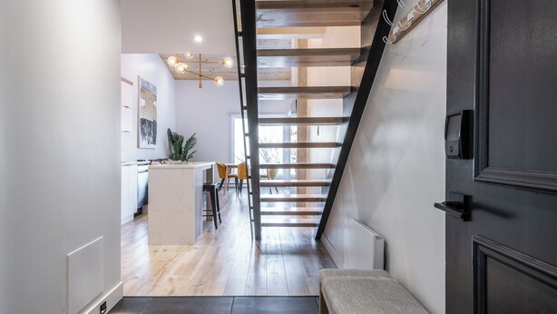 Un interior moderno con una escalera, una zona de cocina y un banco.