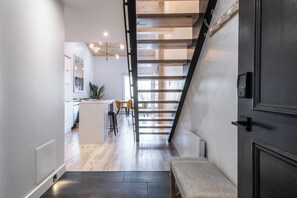 Un interior moderno con una escalera, una zona de cocina y un banco.