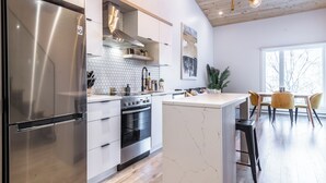 Una cocina moderna con refrigerador de acero inoxidable, horno integrado y armarios blancos.