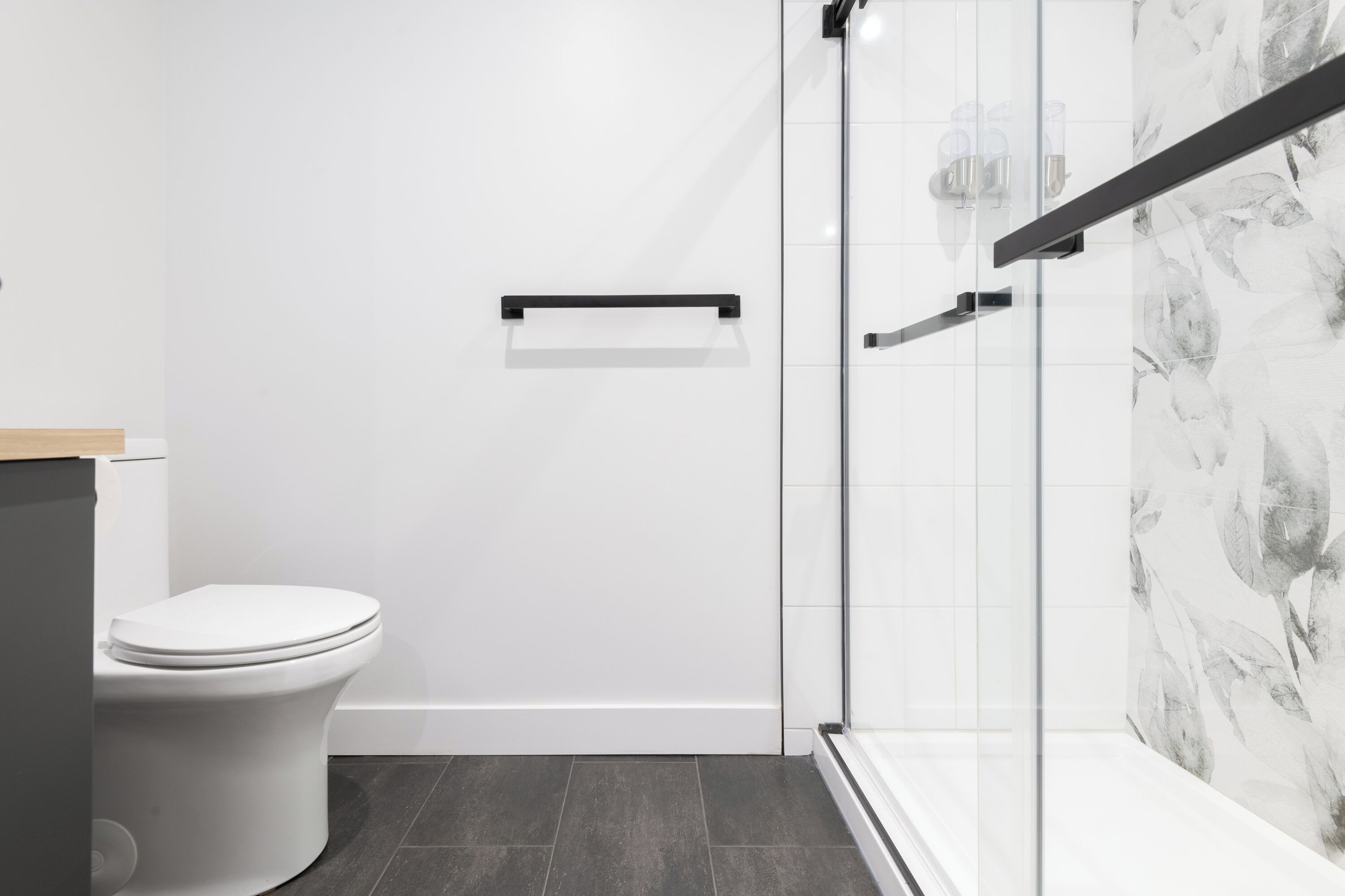 Een moderne badkamer met toilet, douchecabine van glas en een betegelde wand.