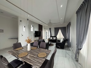 A modern living room with a dining area, a flat-screen TV, and a chandelier. - Ayan Villas  luxurious One bedroom penthouse with a beach view! (Oshiyie)