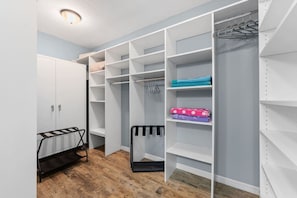 Ein begehbarer Kleiderschrank mit offenen Regalen, einer Kleiderstange und einer Sitzbank.