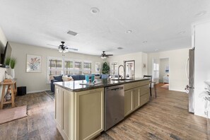 A spacious kitchen with a central island, a dishwasher, and a refrigerator. - 3BR Coastal Retreat | Heated Pool + Game Room (Bradenton)