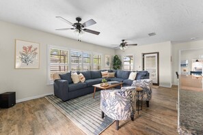 A spacious living room with a sectional sofa, two armchairs, a coffee table, and a ceiling fan. - 3BR Coastal Retreat | Heated Pool + Game Room (Bradenton)
