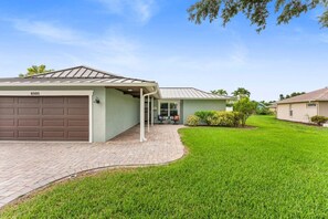 A single-story house with a garage, a paved driveway, and a well-maintained lawn. - 3BR Coastal Retreat | Heated Pool + Game Room (Bradenton)