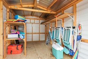 A compact room with a wooden ceiling, a bunk bed, a shelf with various items, and a wall-mounted rack with bags. - 3BR Coastal Retreat | Heated Pool + Game Room (Bradenton)