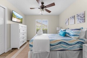 A bedroom with a bed, a ceiling fan, a dresser, a window, and artwork on the wall. - 3BR Coastal Retreat | Heated Pool + Game Room (Bradenton)