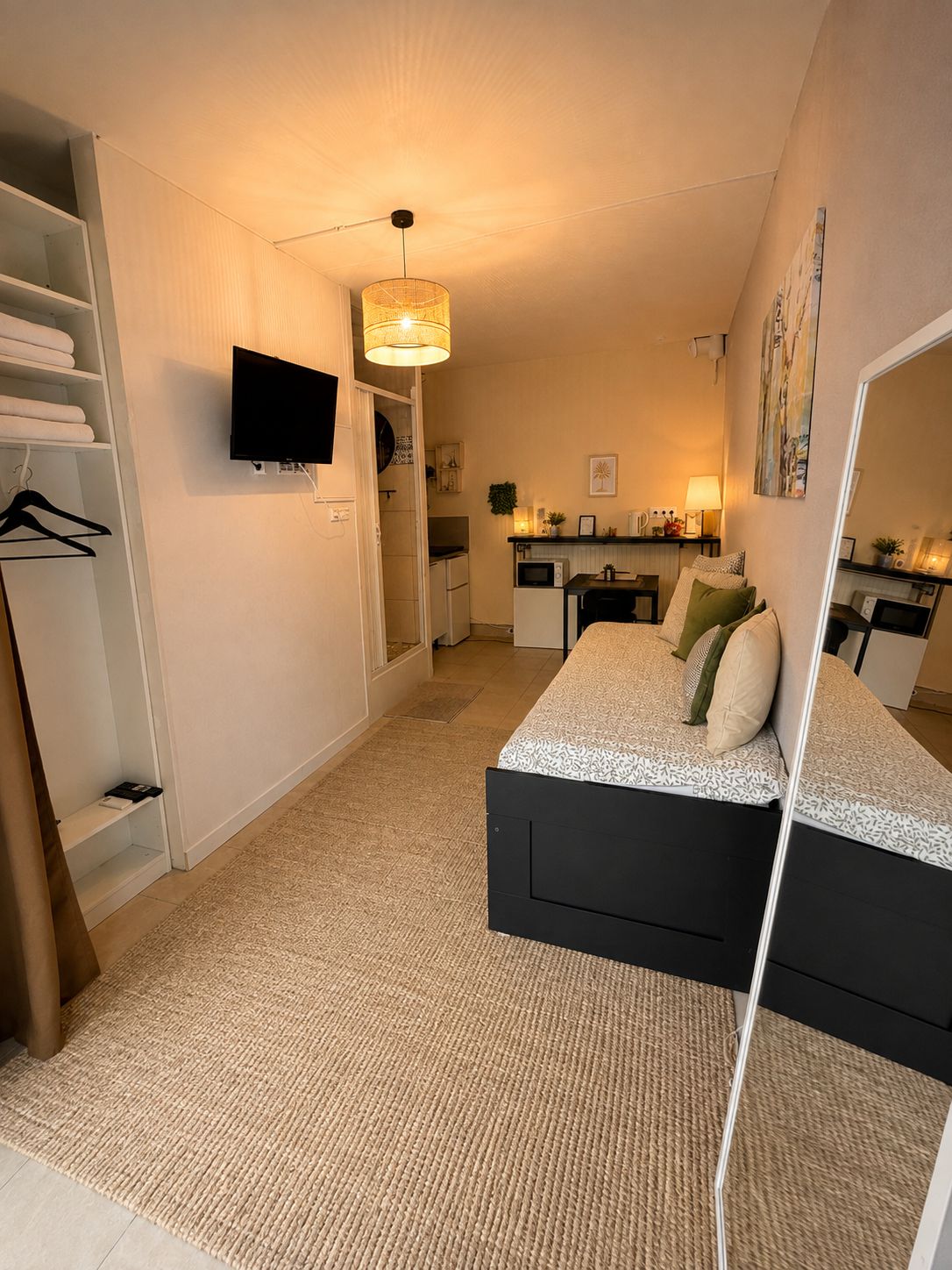 Ein Schlafzimmer mit einem Bett, einem Fernseher, einem Schreibtisch und einer Küchenzeile.