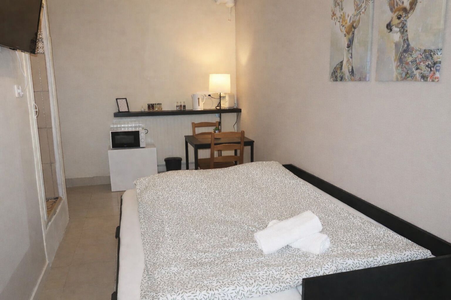 Ein Hotelzimmer mit einem Bett, einem Schreibtisch mit Lampe, einer Mikrowelle und einem Sessel.
