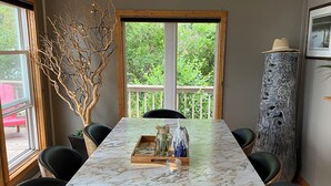 A dining area with a marble table, black chairs, a decorative tree, and a tall column with intricate carvings.
