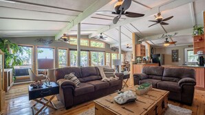 A spacious living area with two sofas, a coffee table, and ceiling fans.