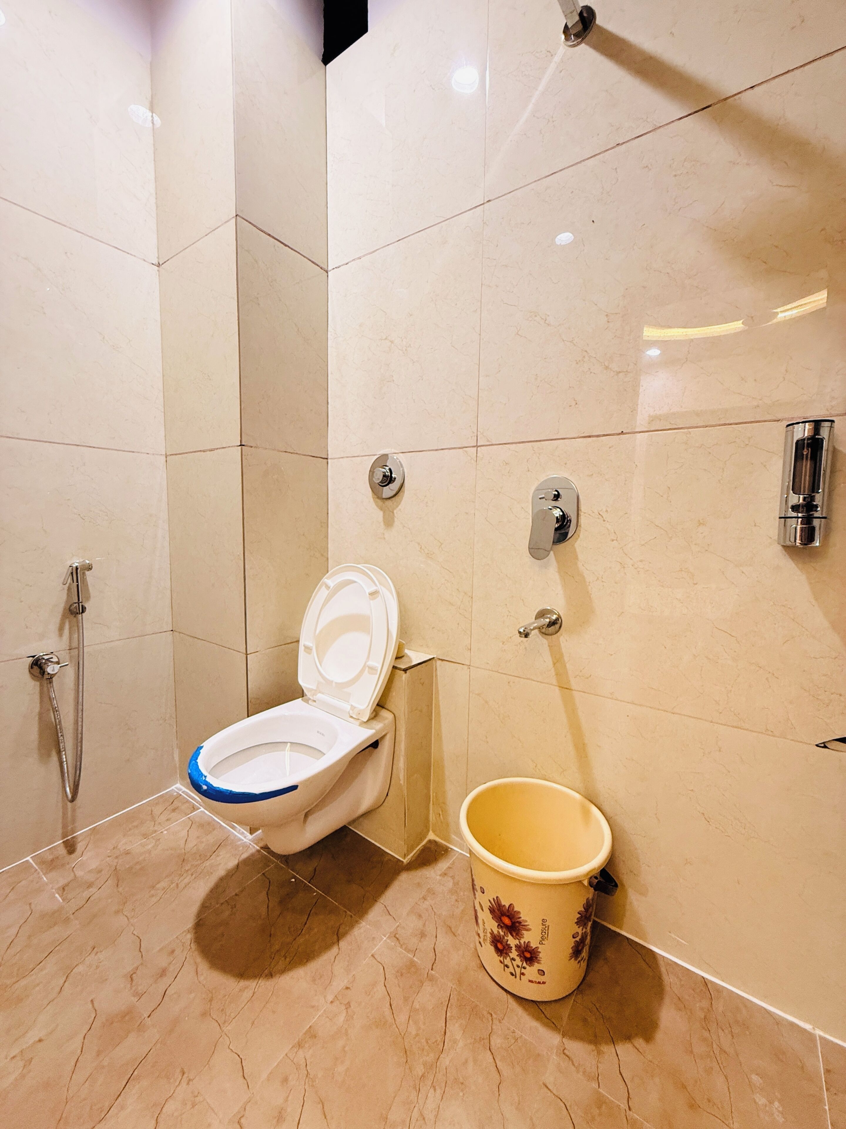Een badkamer met een toilet, een douche en een emmer.