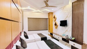A modern hotel room with two beds, a flat-screen TV, a ceiling fan, and a marble accent wall. - Hotel Hira Palace (Ujjain)