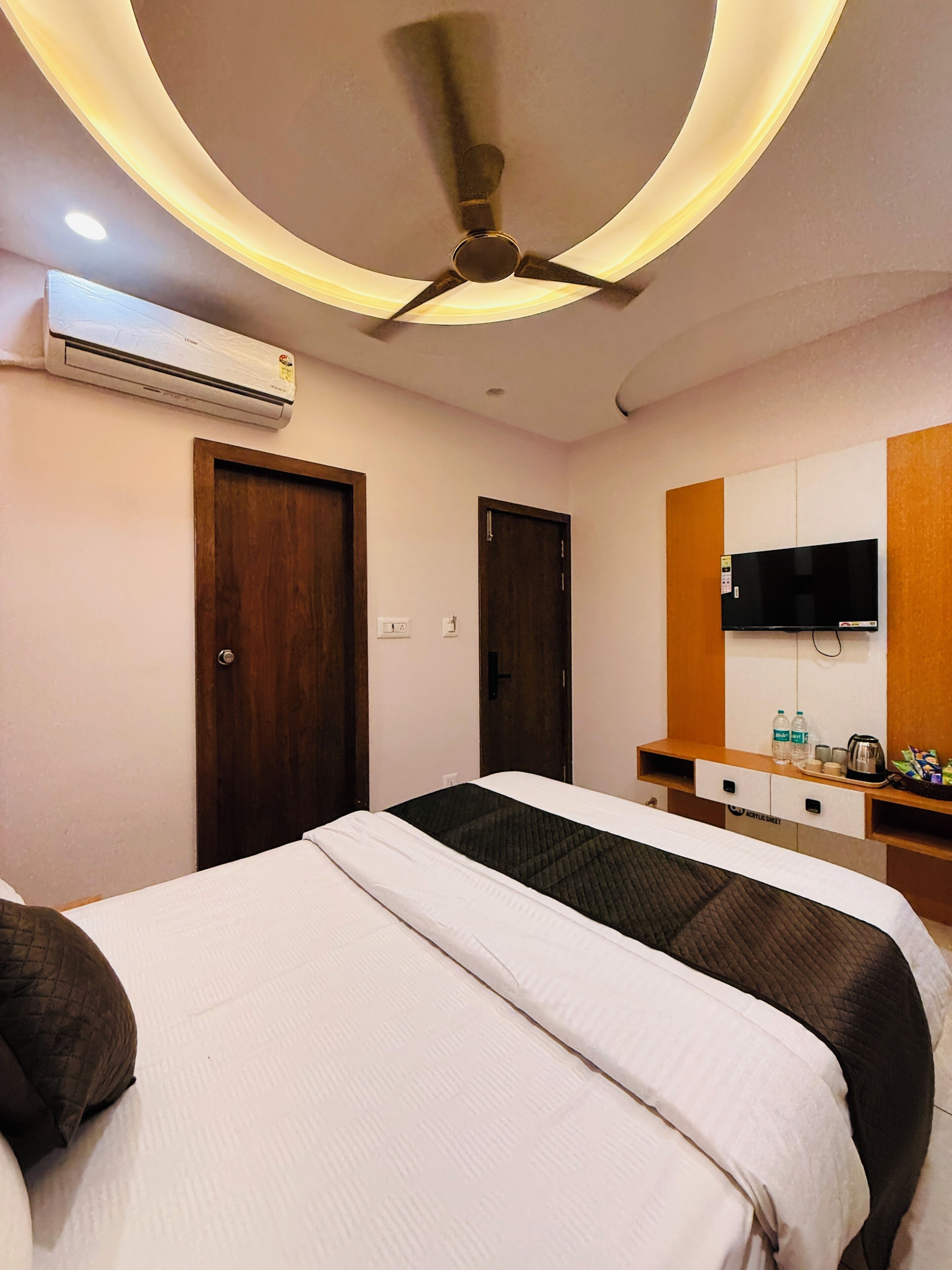 Une chambre d’hôtel équipée d’un lit, d’un climatiseur, d’un ventilateur de plafond, d’une télévision et d’un mini-bar.