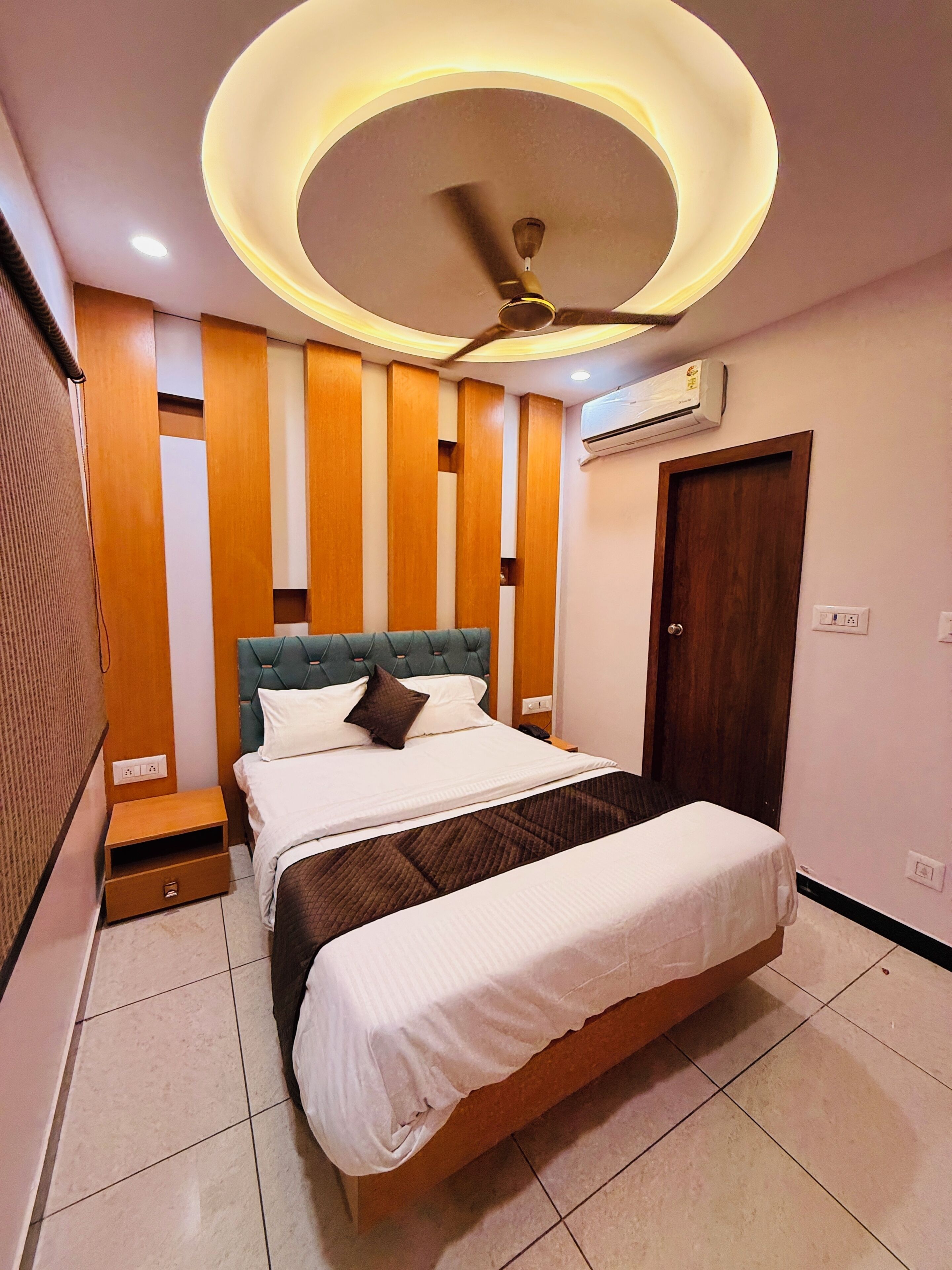 A modern bedroom with a bed, a ceiling fan, and an air conditioning unit.