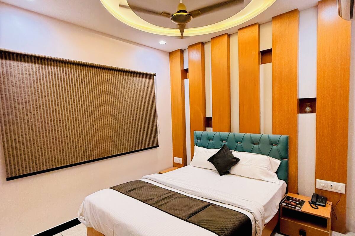 Ein modernes Hotelzimmer mit einem großen Bett, einem Deckenventilator, einem Nachttisch mit Telefon und einer wandmontierten Klimaanlage.