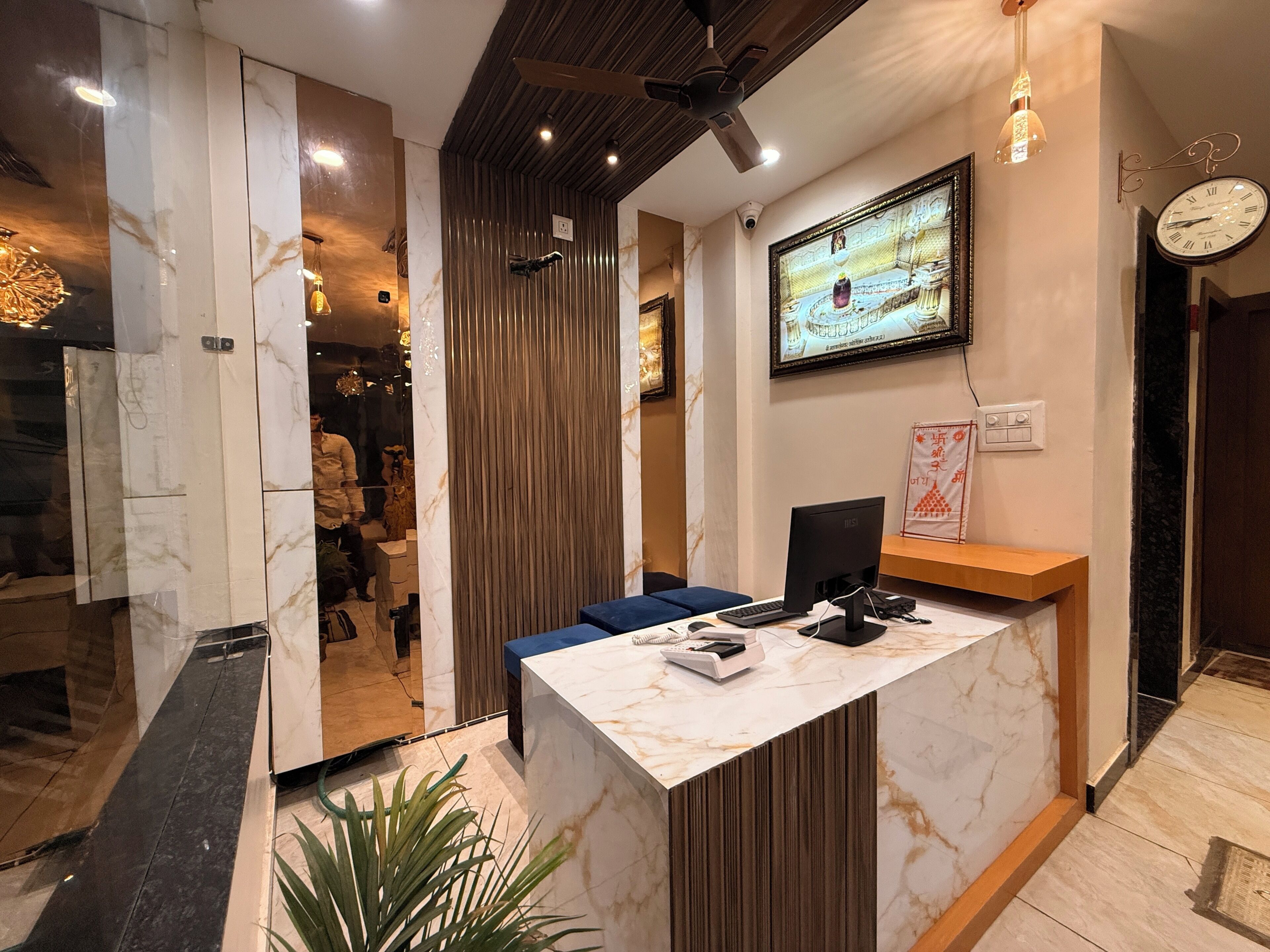 A reception desk with a computer, phone, and a clock on the wall.