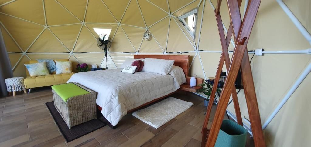 A tent-style room with a bed, a wooden ladder, and a sofa.