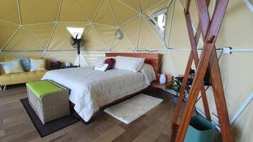 A tent-style room with a bed, a wooden ladder, and a sofa.