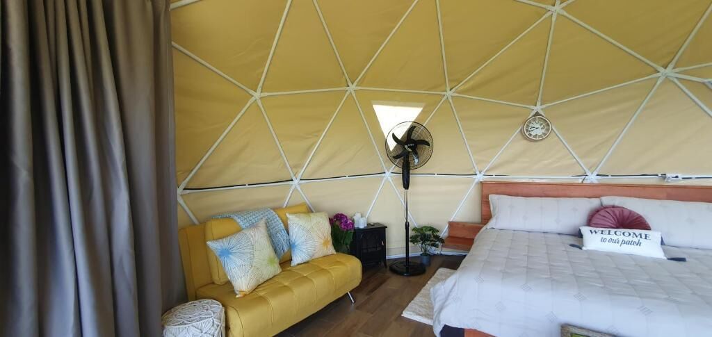 Alojamiento con carpa que incluye una cama, un sofá, un ventilador y un reloj en el techo.