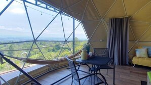 A room with a large window, a hammock, a table, a yellow sofa, and a view of the landscape. - Ararat Eco Farm (Sabalito)