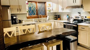 Una cocina con gabinetes blancos, un refrigerador de acero inoxidable, una cafetera y una ventana con vistas.